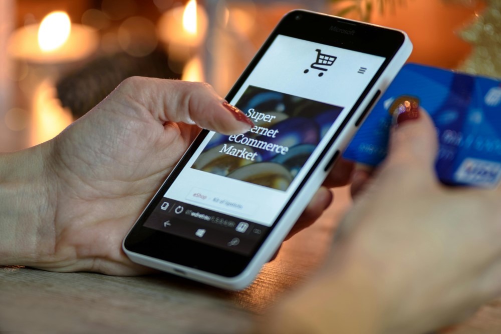 A person holding a phone open to an ecommerce page with a credit card in their other hand.