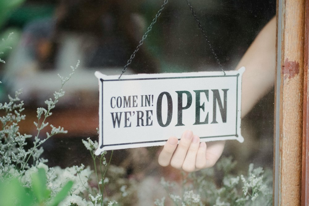 Person flipping a sign to OPEN in a store window