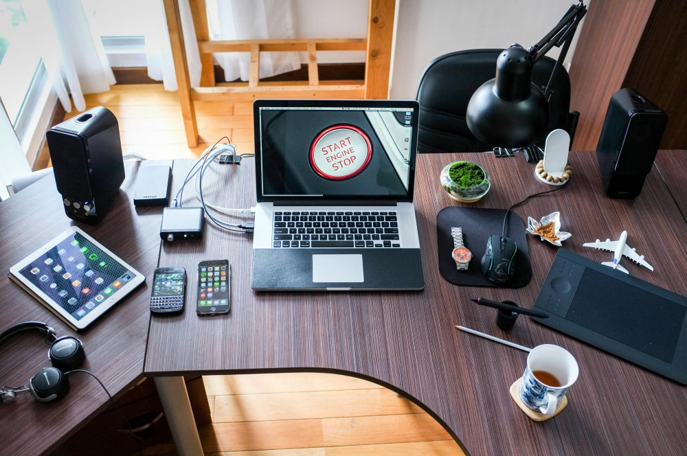 A dark wooden desk with various electronics on top