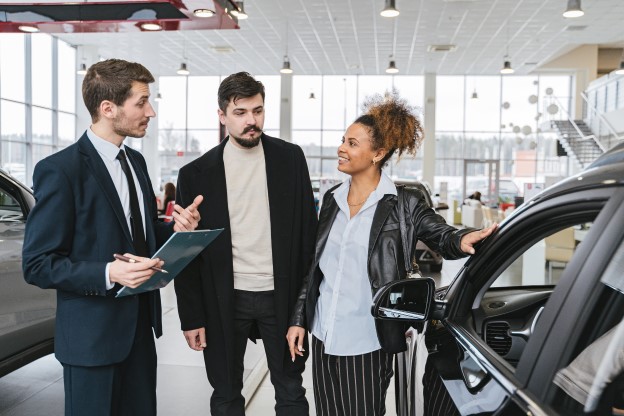 A man talking to potential customers in a car dealership