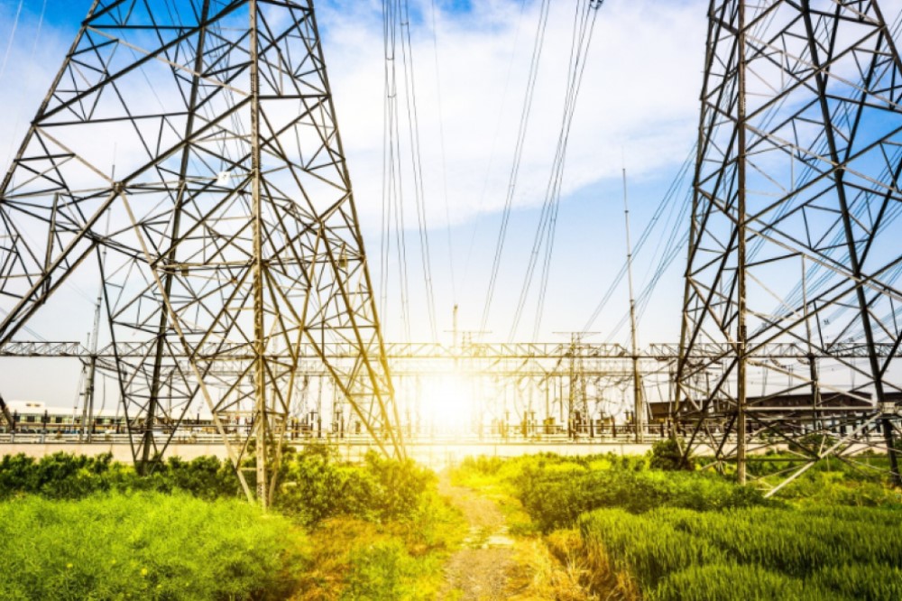 Power lines leaving a power plant in front of a sunset