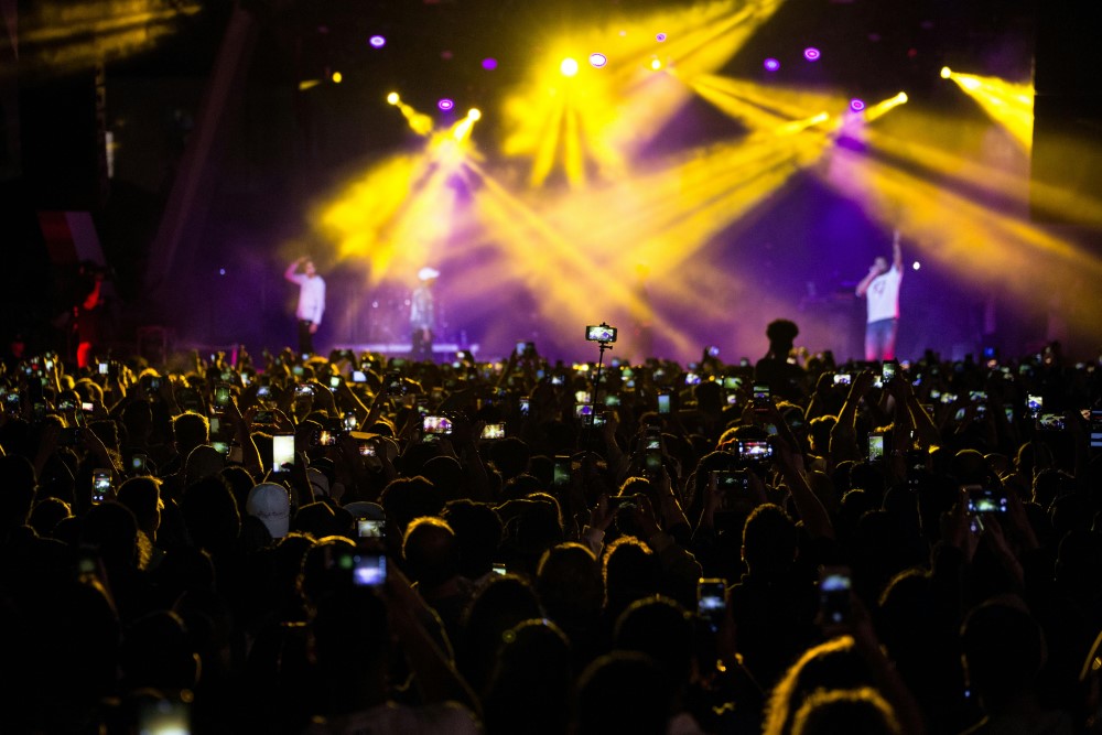 A crowd lit by yellow and purple lights at a band concert