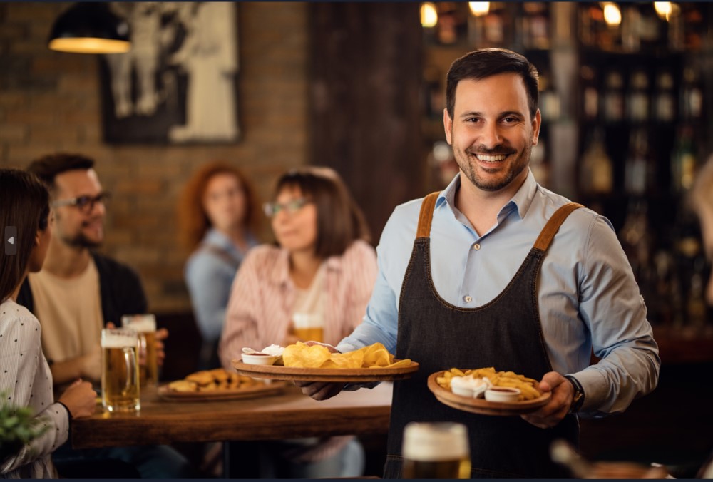 A waiter delivering food to a customer's table in a restaurant