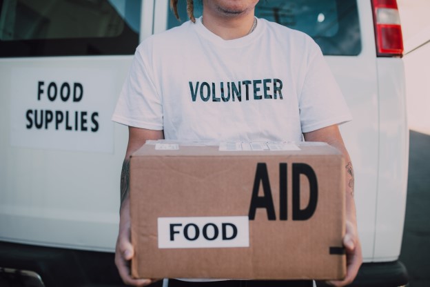 A volunteer at a nonprofit holding a box of food and supplies
