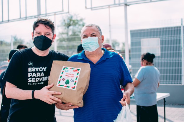A volunteer at a nonprofit organization handing a man a bag of food