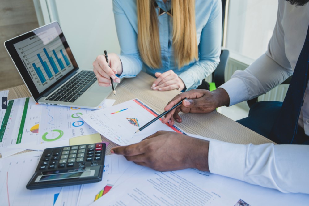 Two professionals comparing different graphs and charts over a desk